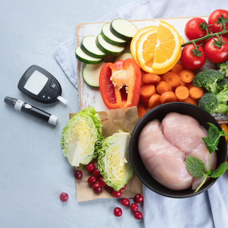 Plusieurs aliments (poulet, poivrons, tomates, oranges, etc) sont disposés près d'un glucomètre