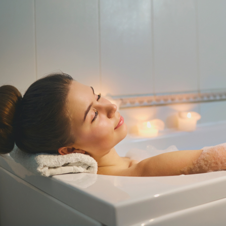 Une femme se détend dans un bain chaud avec des huiles essentielles