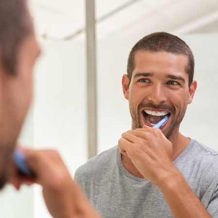 un homme se brosse les dents devant sa glace