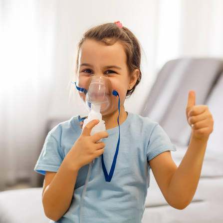 Une enfant qui utilise une chambre d'inhalation met son pouce en l'air