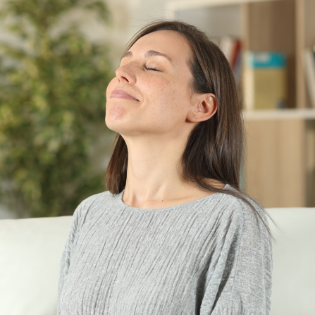 Une femme assise dans son canapé prend une grande respiration