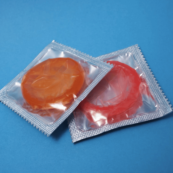 2 préservatifs rouge et orange dans un emballage transparent sur fond bleu