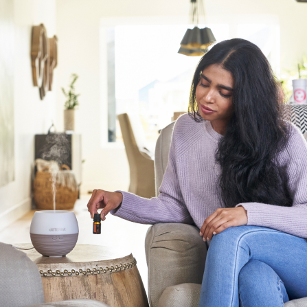 Une femme diffuse des huiles essentielles dans son salon pour combattre le rhume