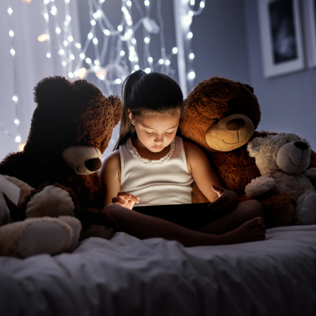 Une petite fille regarde une tablette avant de dormir