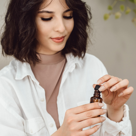 Une femme ouvre un flacon d'huile essentielle