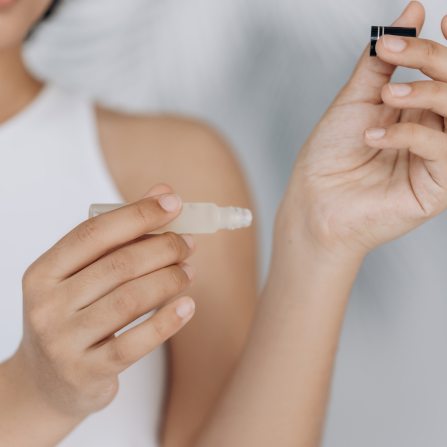 Une femme s'applique de l'huile essentielle sur les poignets à l'aide d'un roll-on